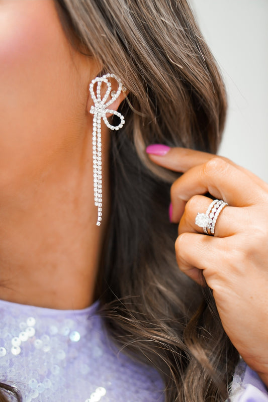 up close shot of girl wearing bow shaped earrings with diamond detailing 