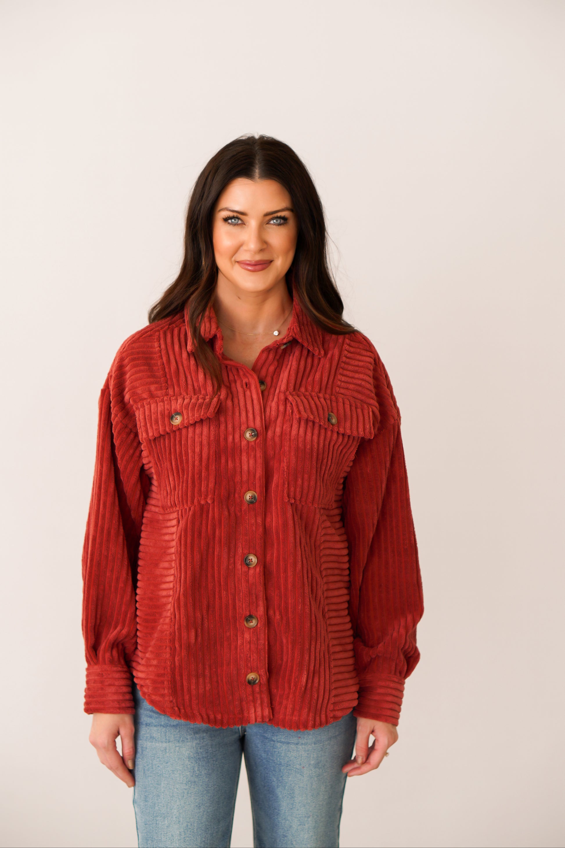 Brunette girl in a rust color shacket with brown buttons. 