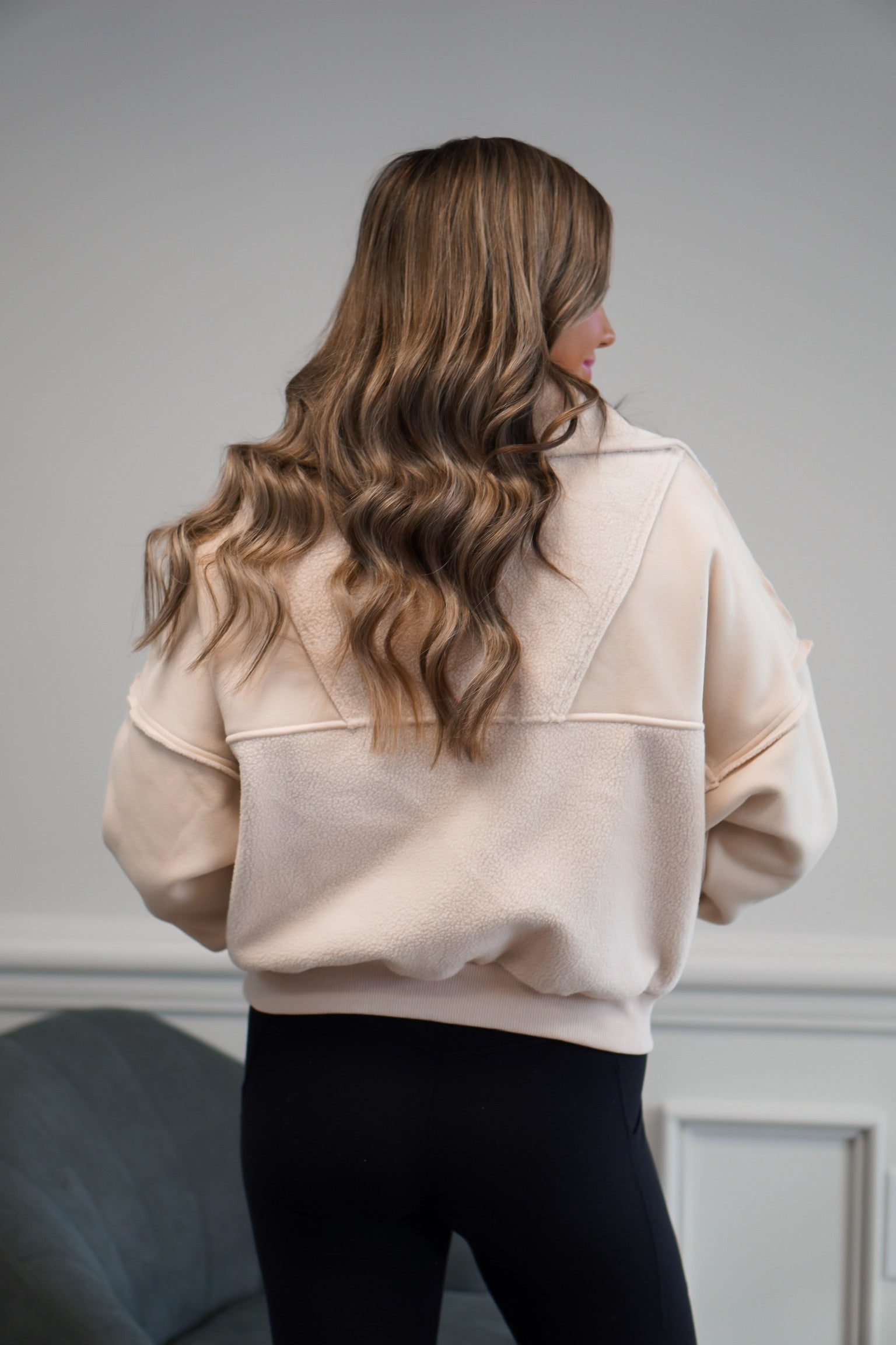 girl standing facing away from the camera showing the back of the cream pullover